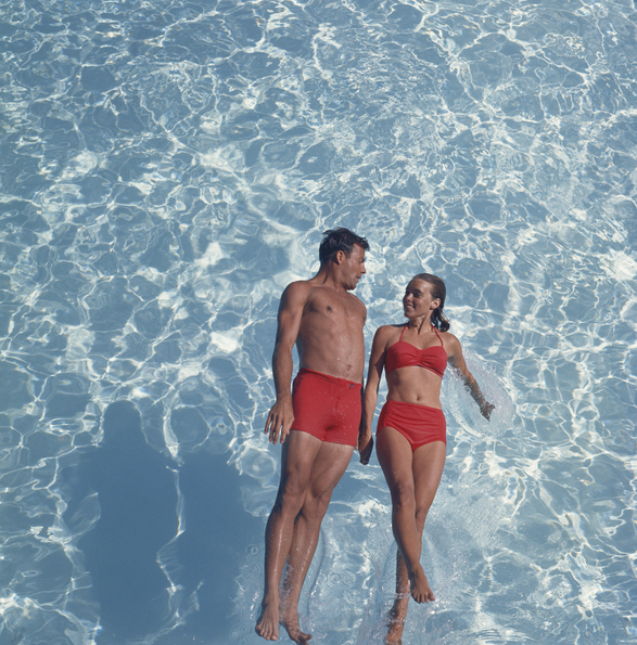 Attractive Dateable Couple swimming in a pool wearing red swimsuits.